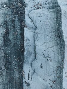 Top view of abstract background of dry uneven rocky surface in blue and white color