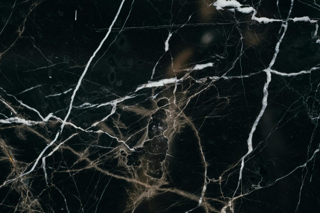 pexels-photo-6788338-6788338 Close-up view of a black marble texture, showcasing intricate white veining patterns.