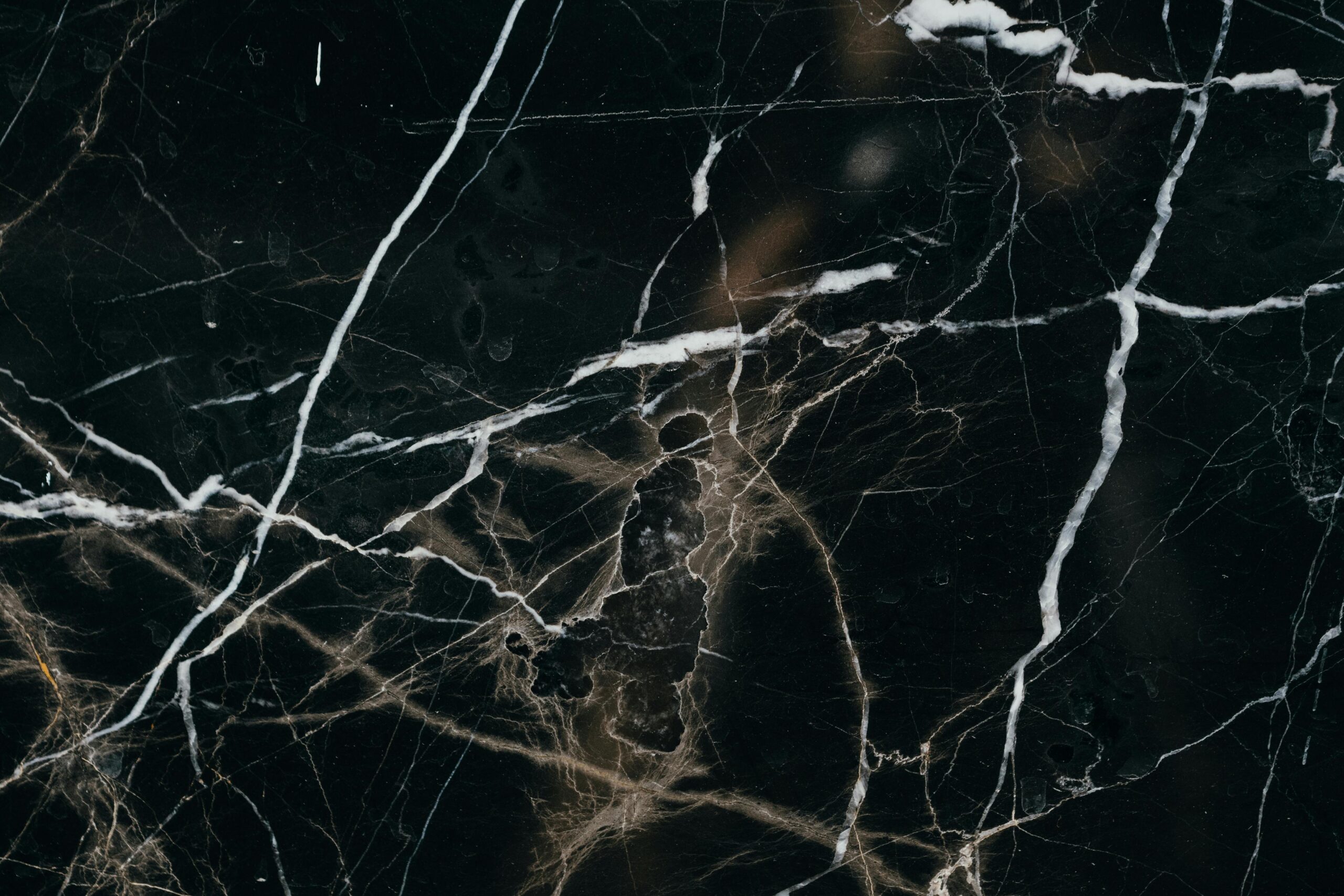 Close-up view of a black marble texture, showcasing intricate white veining patterns.